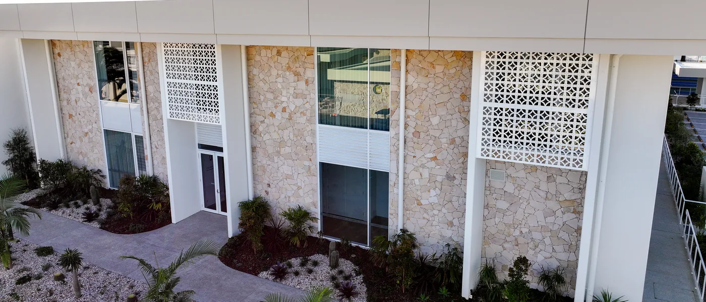 Clubhouse facade with perforated screen panels mounted over random-ashlar stone